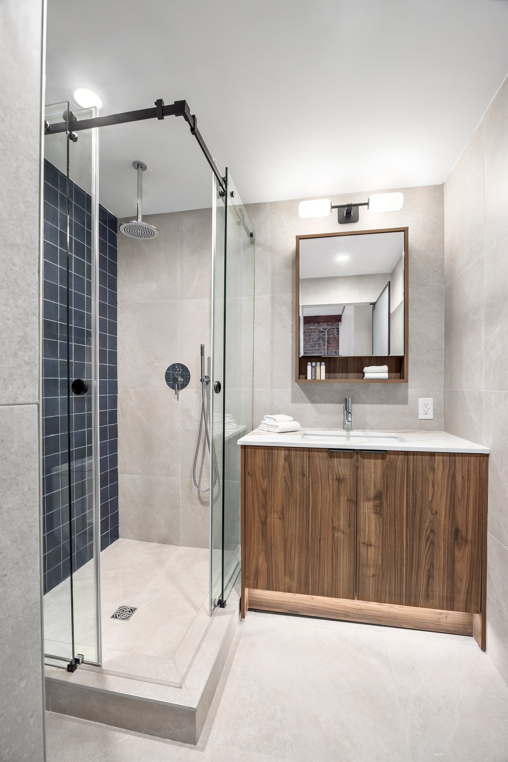 Bath detail — glass rainfall shower, walnut vanity